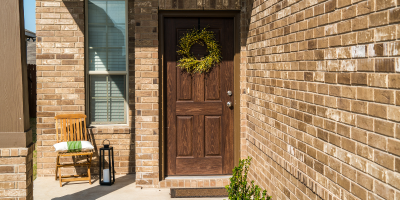 brown front door to home with brick facade